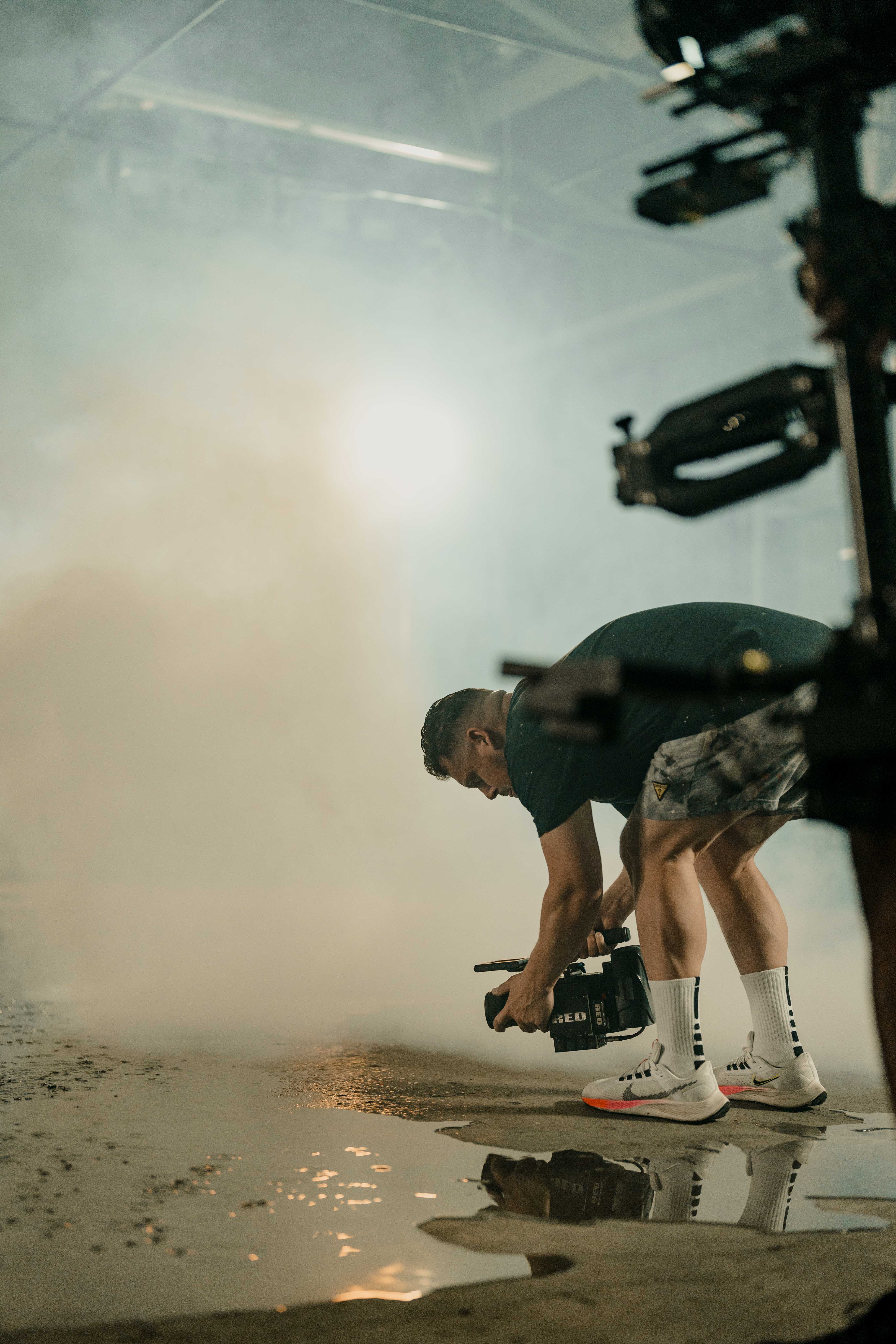 Crew member filming close to the reflective warehouse floor.