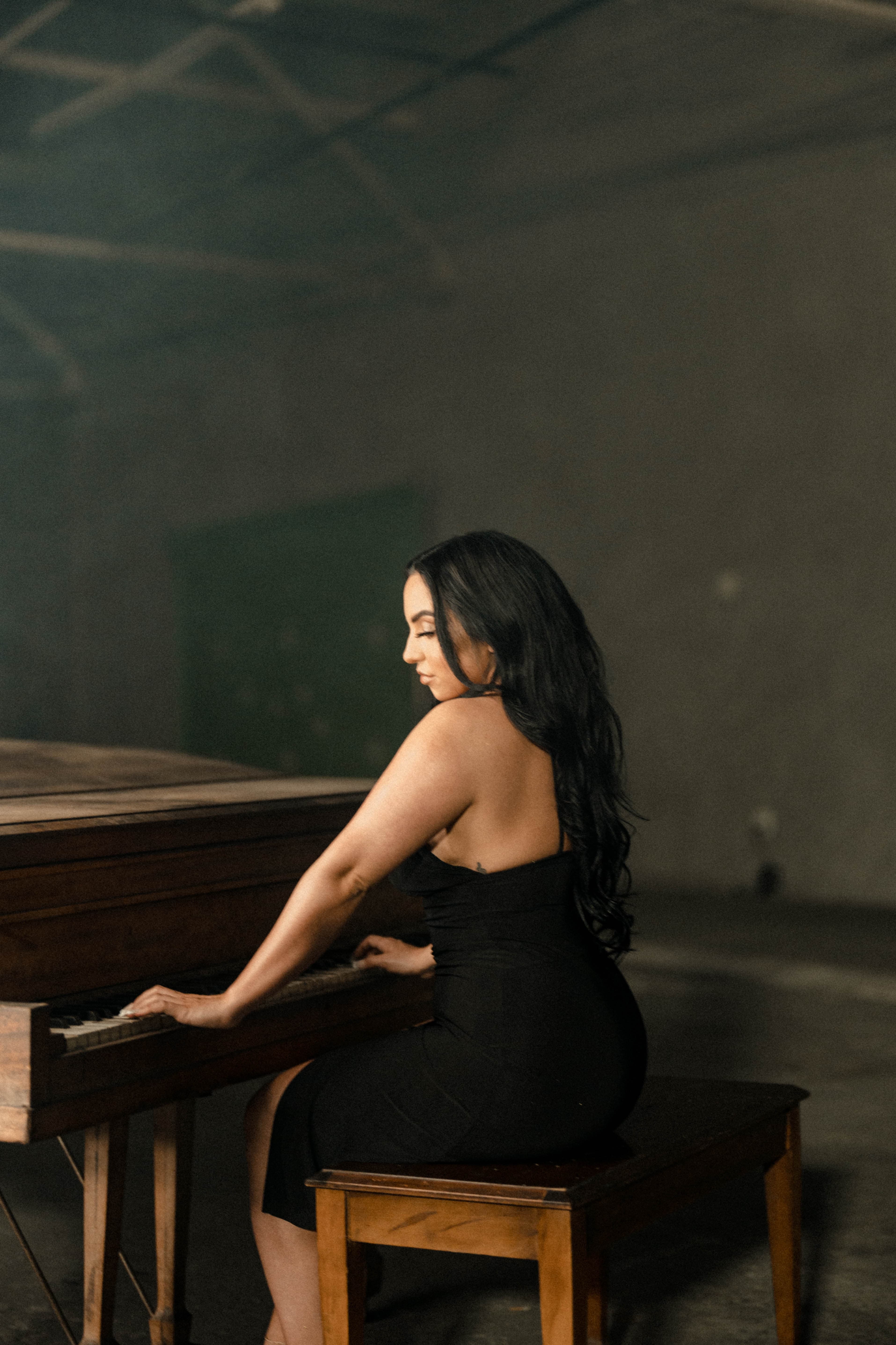 Bianca seated at the piano in a black dress.