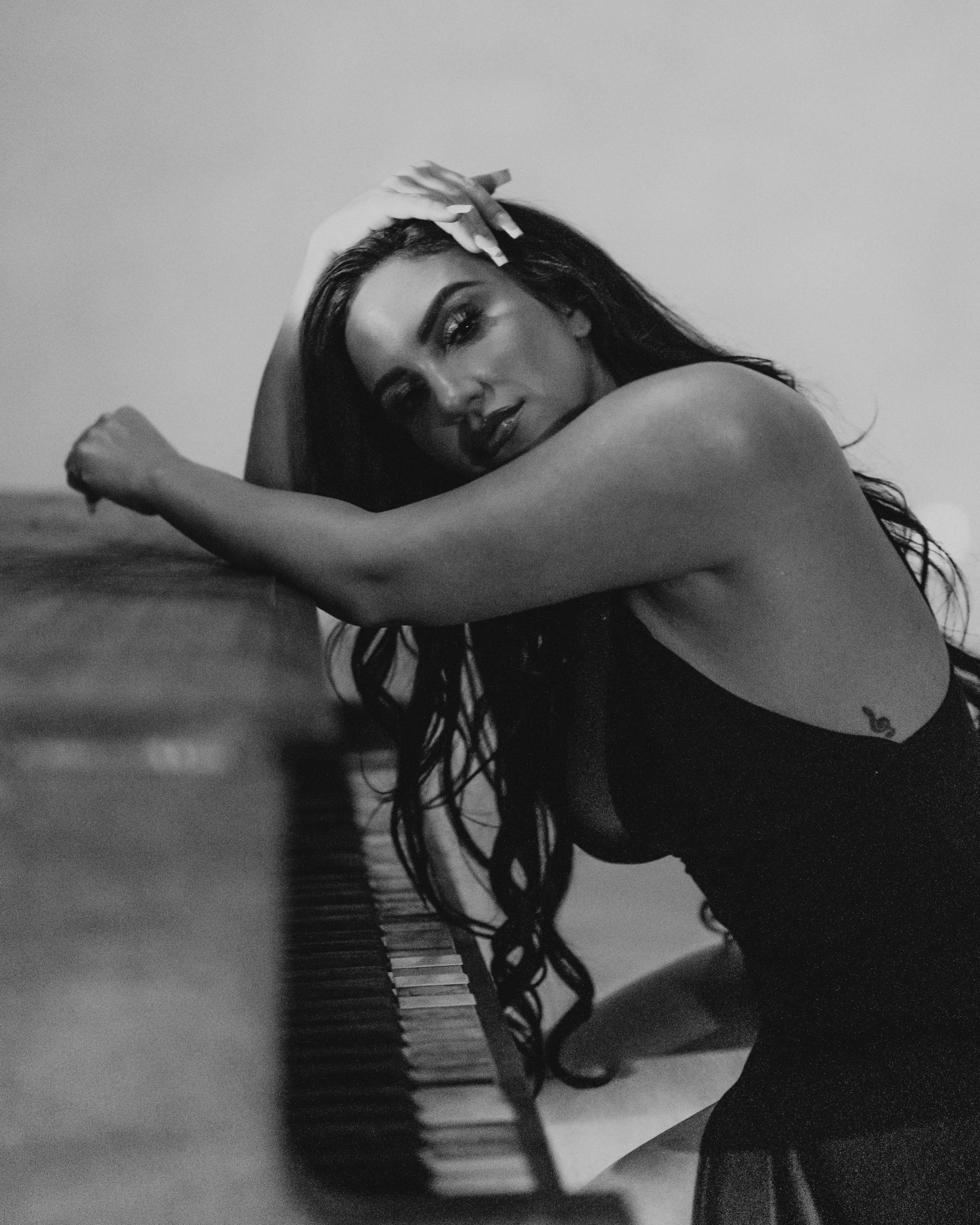 Black-and-white close-up of Bianca leaning across the piano.