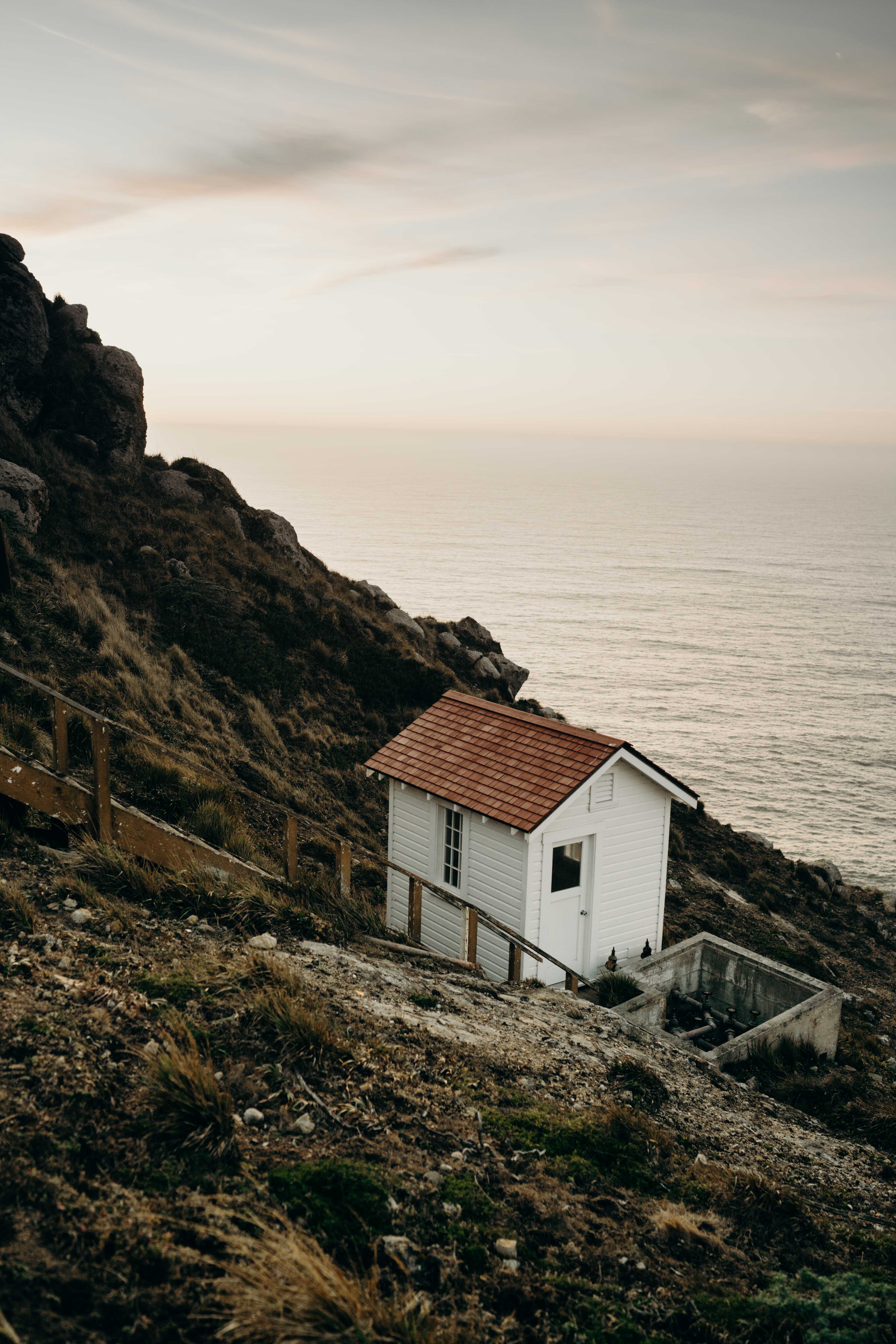 A small white structure on a coastal hillside above the ocean.