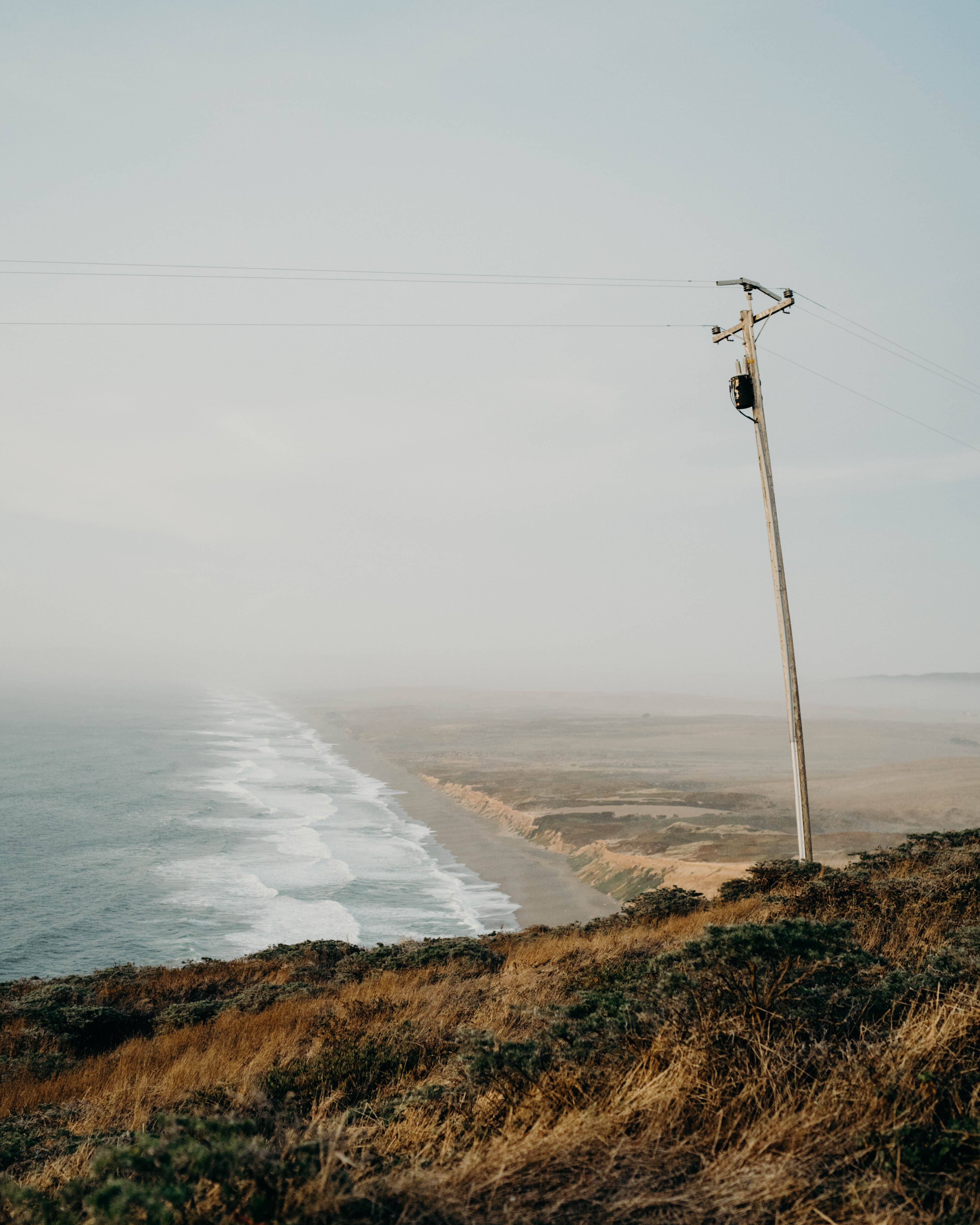 A utility pole overlooking a misty coastline.