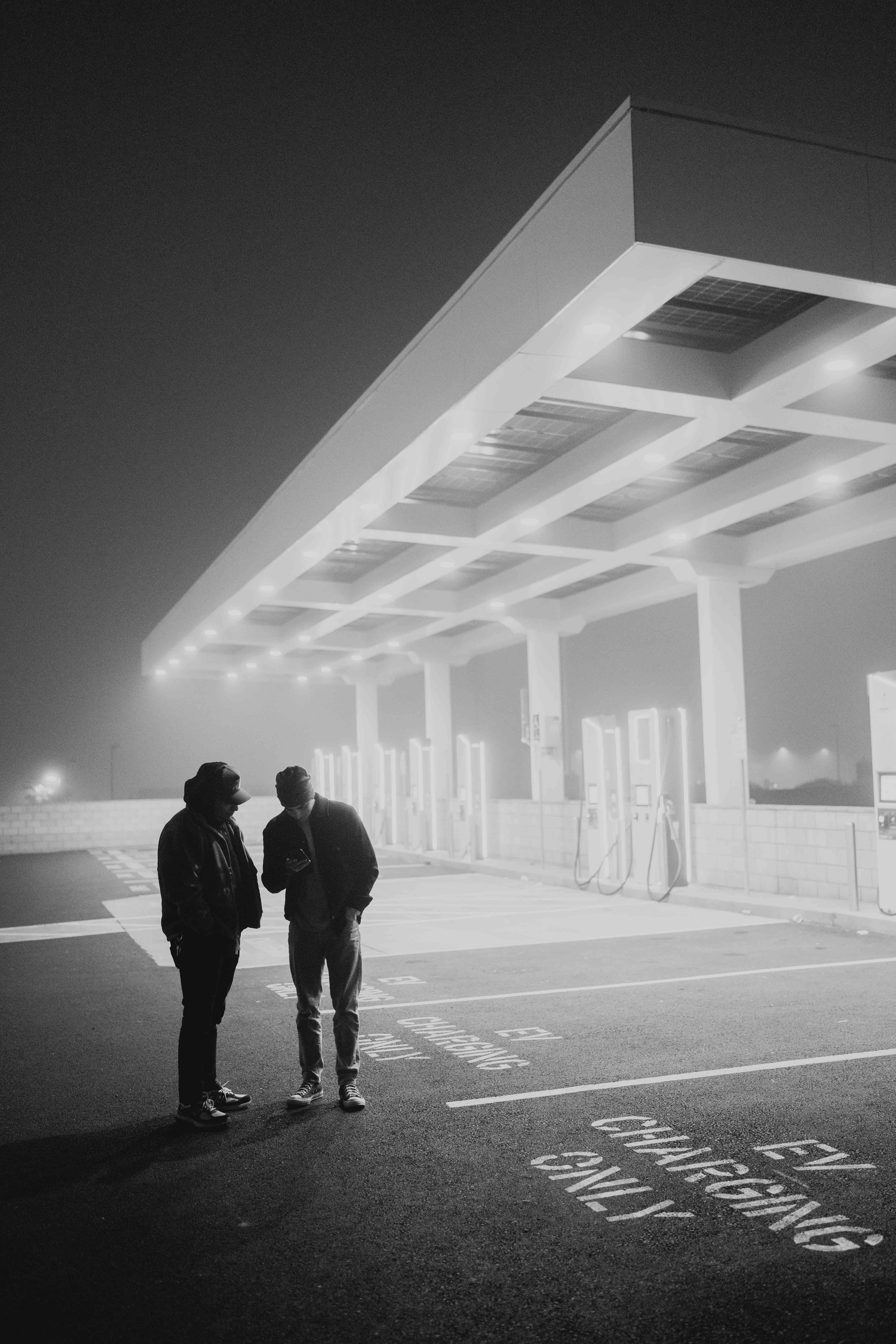 Two people standing beneath illuminated charging bays in fog.