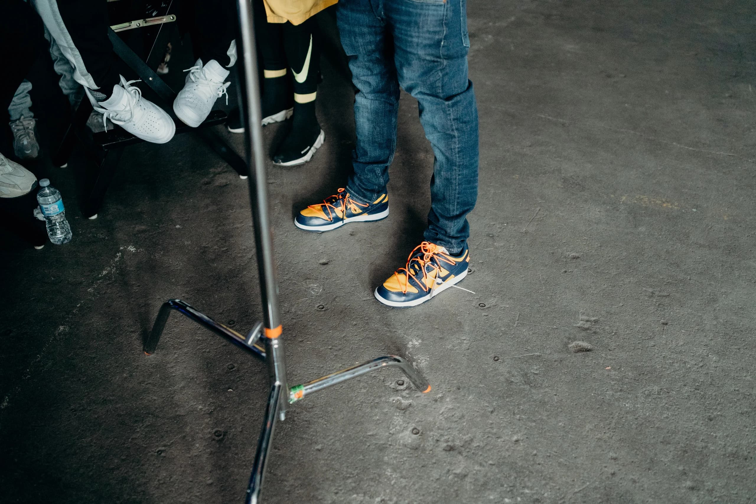 Orange-laced sneakers and a lighting stand on the warehouse floor.