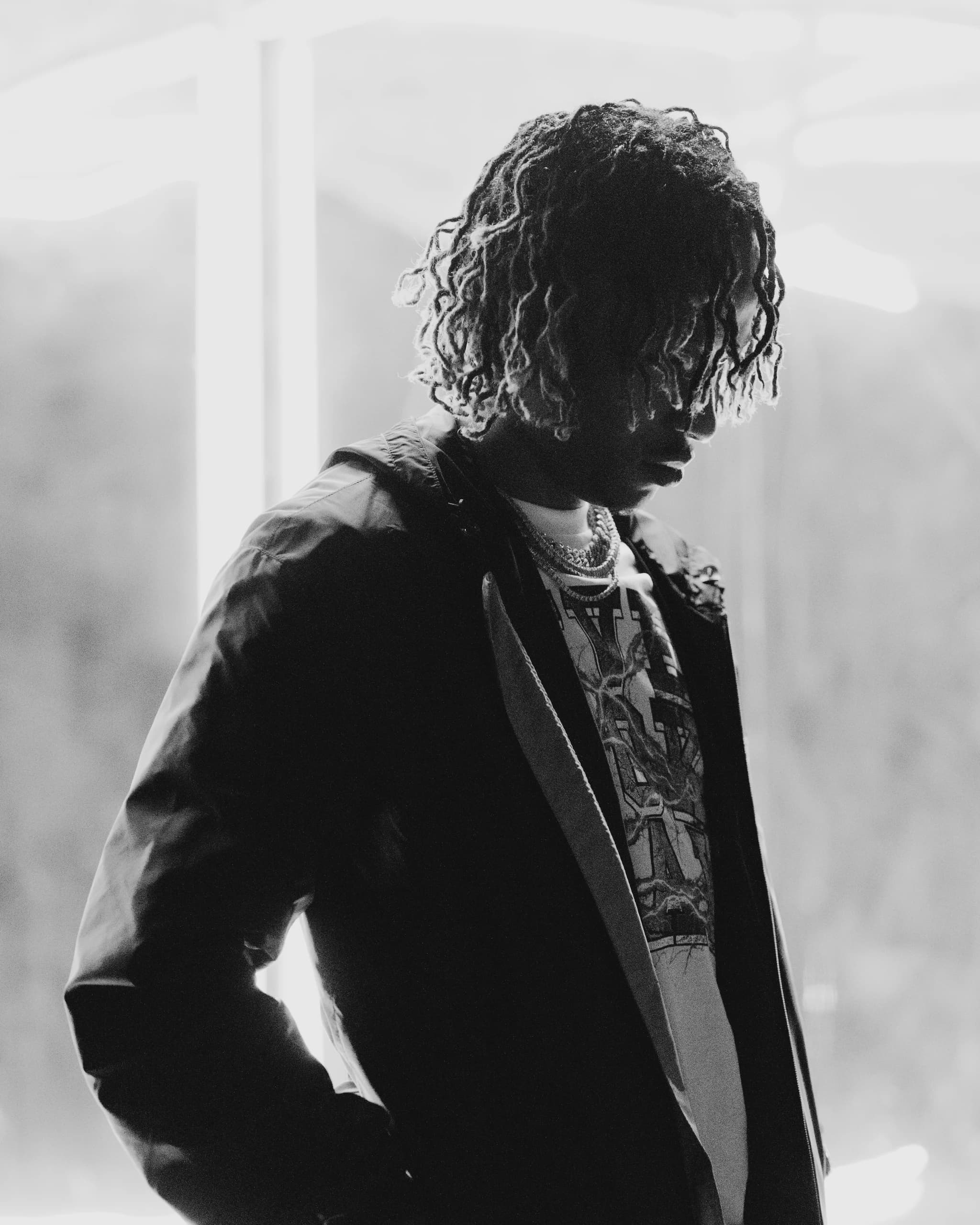 Black-and-white portrait of a performer silhouetted against the illuminated set.