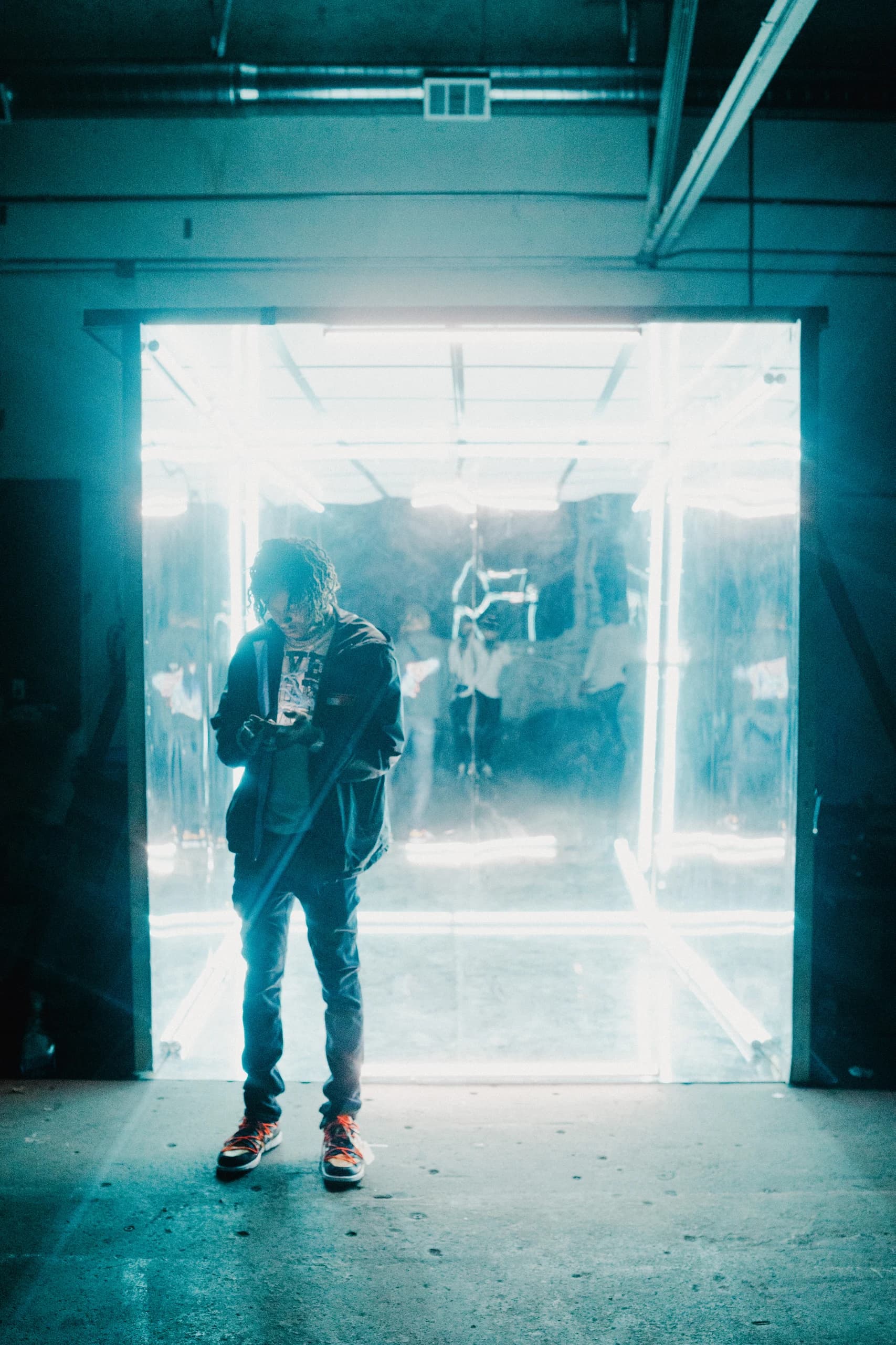 A performer framed by a glowing cyan doorway on set.
