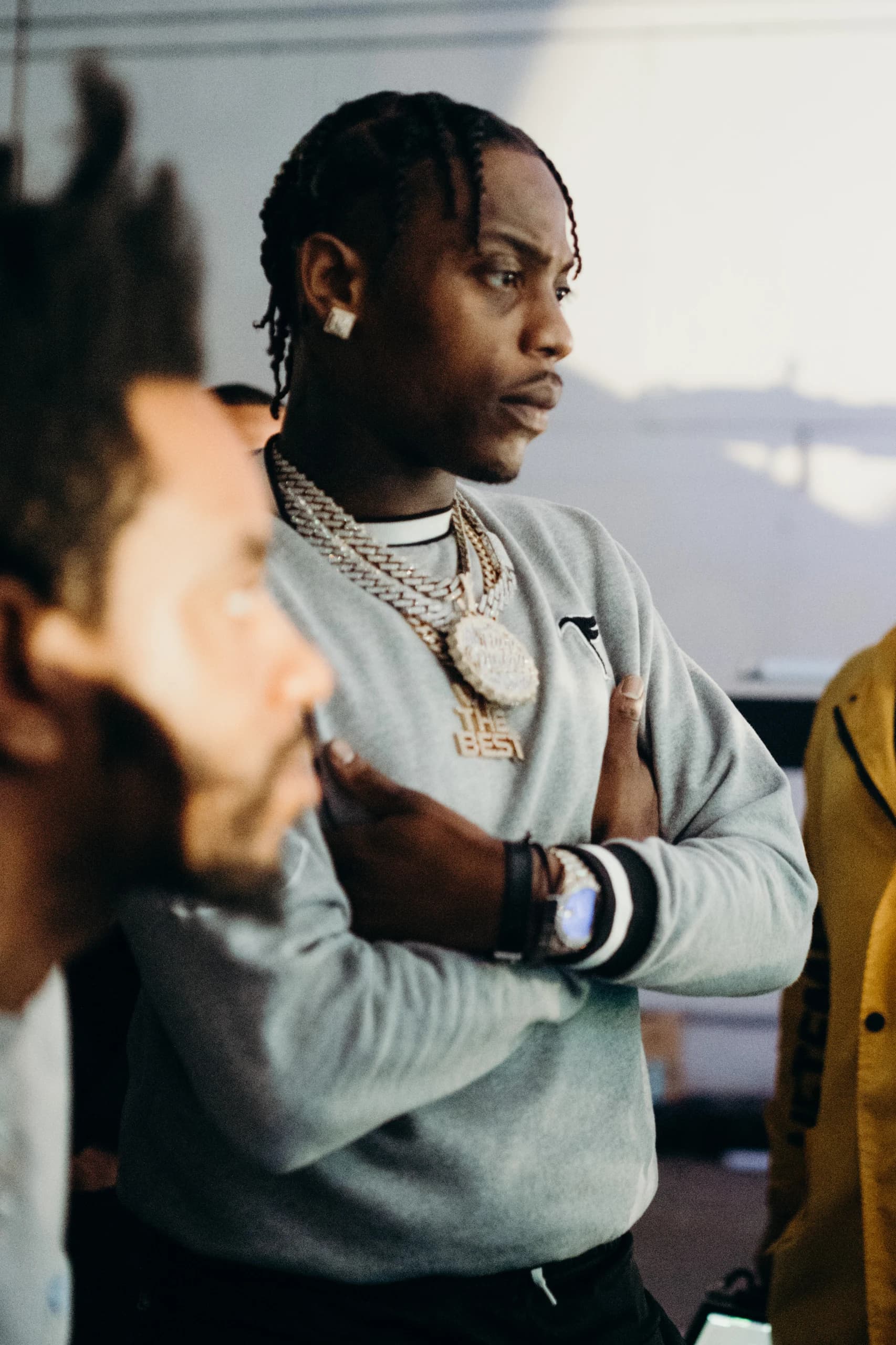 A performer in a grey sweatshirt watches the set with his arms folded.