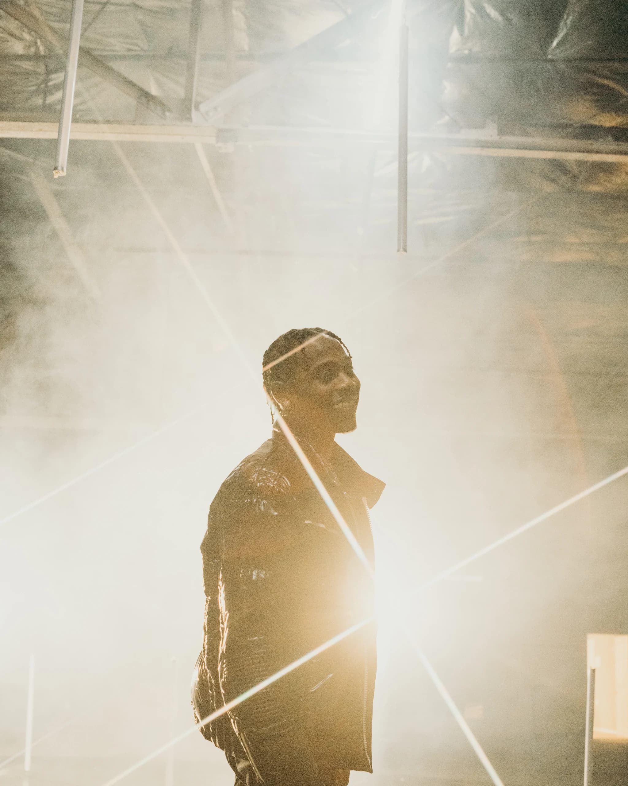 A smiling performer surrounded by golden haze and streaks of light.