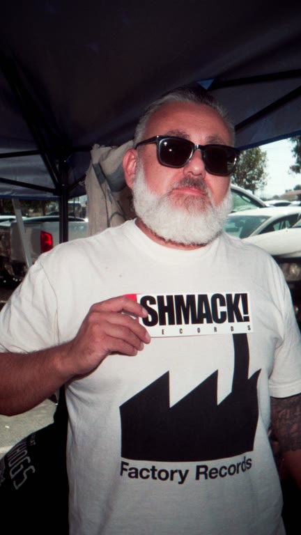 A bearded man in sunglasses at an outdoor record stall.